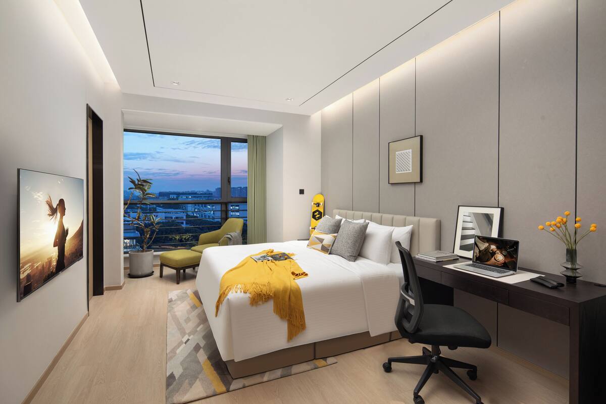 Een moderne hotelkamer met een groot bed, een bureau, een stoel en uitzicht op de stad.