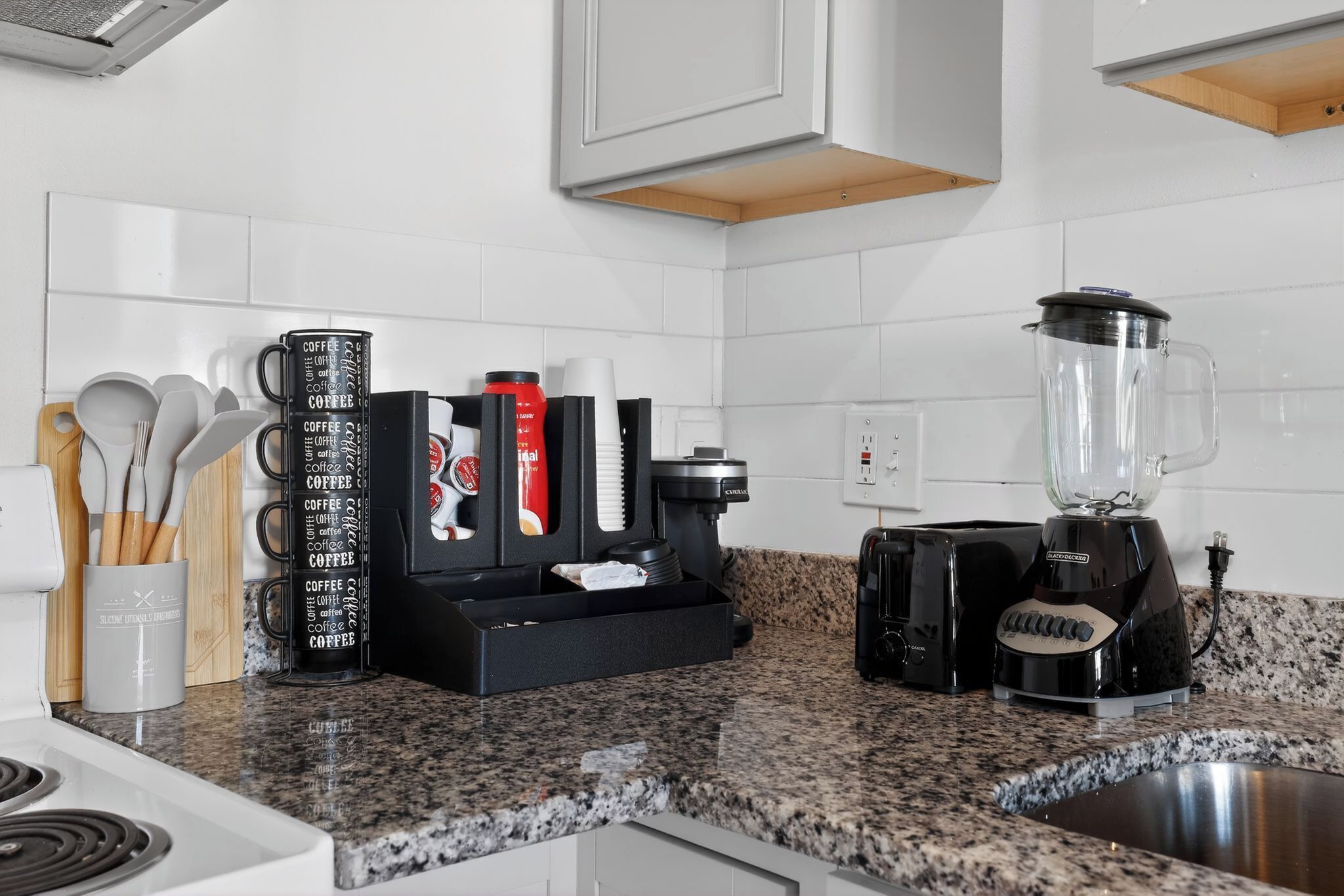 Ett kök med en kaffestation, inklusive en kaffebryggare, en kaffekvarn och koppar, samt en mixer på bänkskivan.