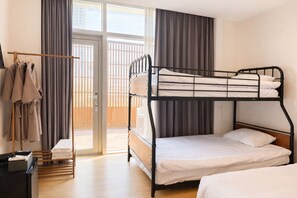 Een slaapkamer met een stapelbed, houten vloer, kledingrek en uitzicht door een glazen deur.