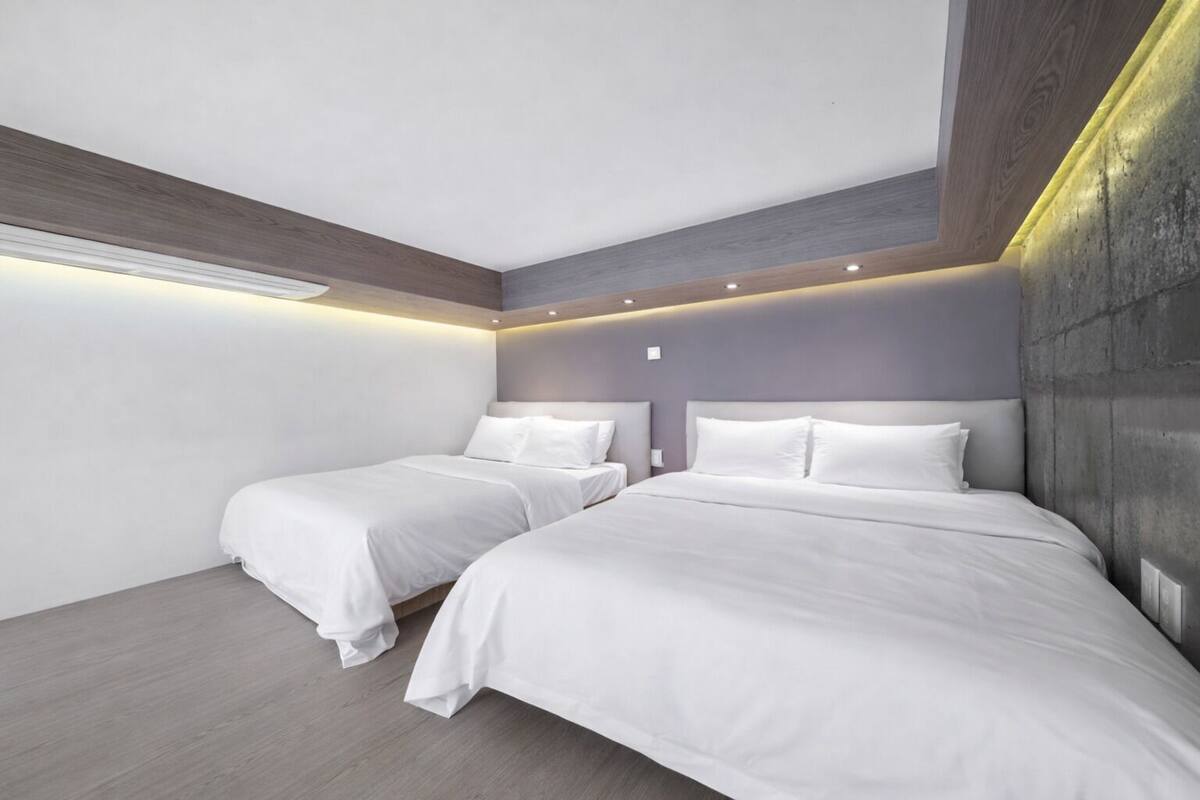 Een moderne slaapkamer met twee bedden, een schuine plafond en inbouwverlichting.