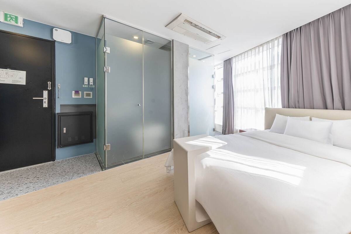 Een hotelkamer met een bed, een kledingkast, een bureau en een raam met gordijnen.
