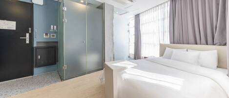A hotel room with a bed, a wardrobe, a desk, and a window with curtains.