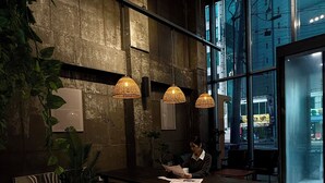 Een modern interieur met een grote tafel, hangende rieten lampen en uitzicht door grote ramen.