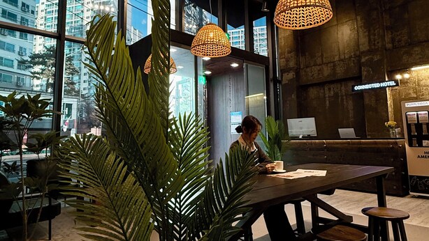 Een modern interieur met grote ramen, hangende rieten lampen en een zithoek met krukken.