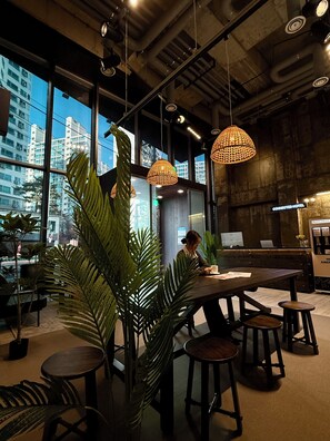 Een modern interieur met grote ramen, hangende rieten lampen en een zithoek met krukken.