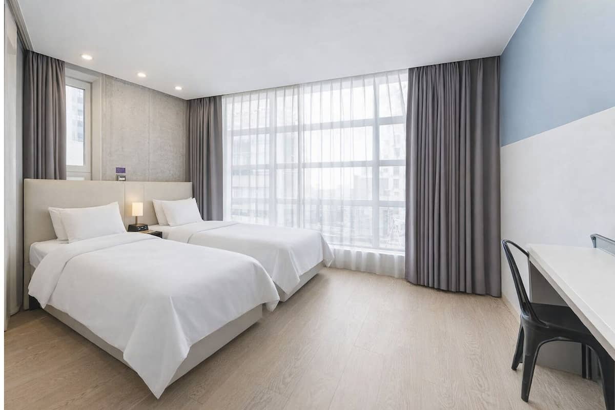 Een hotelkamer met twee bedden, een bureau en een stoel.
