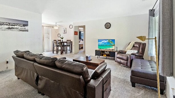 Ein Wohnzimmer mit braunem Ledersofa, einem Couchtisch, einem Fernseher und einem Essbereich mit Stühlen und Tisch.