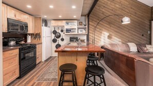 Une cuisine compacte dotée d’un îlot central, d’un coin repas avec un canapé et d’un mur en bois.