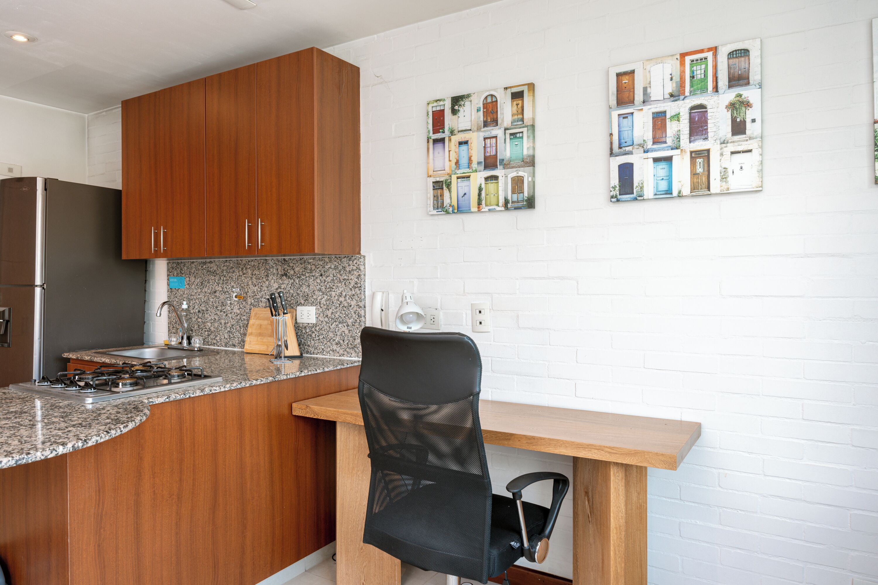 A kitchen with wooden cabinets, a granite countertop, a gas stove, and a black mesh chair.