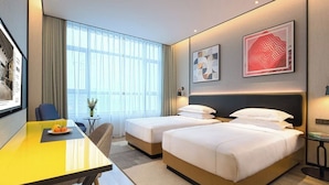 A hotel room with two beds, a dining table, a small table with a vase, and artwork on the walls. - The Hotel V Wuxi (Wuxi)