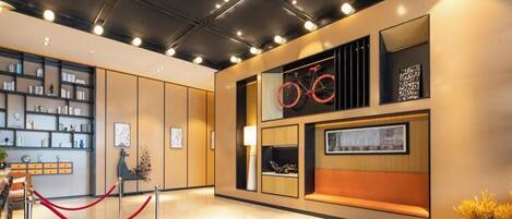 A modern lobby with a seating area, a bookshelf, and a bicycle-themed wall decoration.