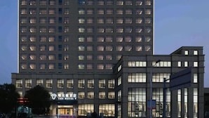 A multi-story hotel building with a modern design, featuring a prominent entrance and a well-lit facade. - The Hotel V Wuxi (Wuxi)