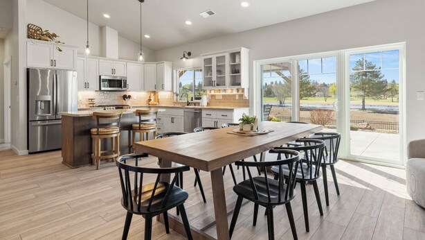 A modern kitchen with a large island, stainless steel appliances, and a view of a lake through large sliding glass doors. - Harbor House with Hottub on 18th Hole (Klamath Falls)