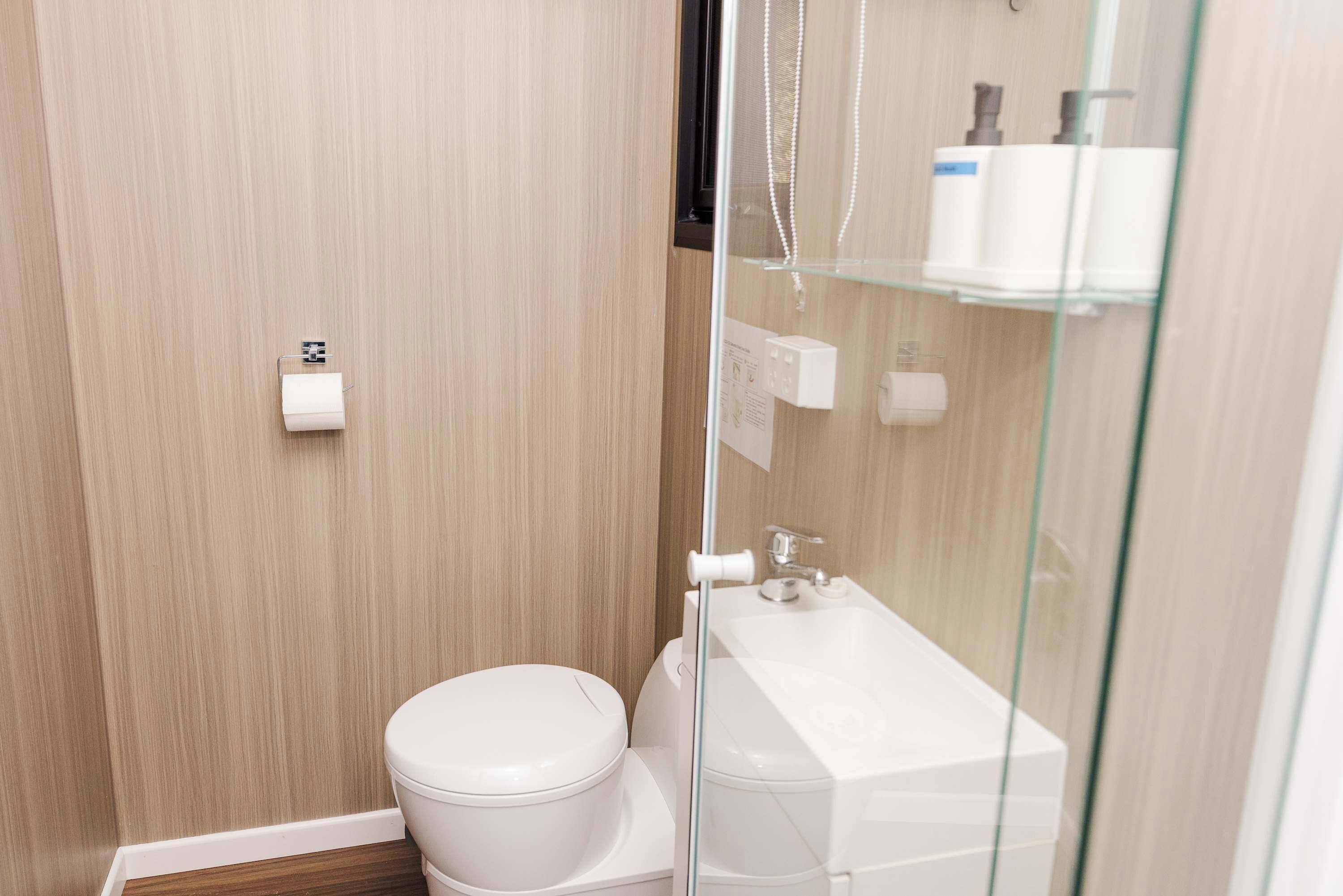 Une salle de bain moderne avec des toilettes, une douche à parois de verre et un lavabo blanc.