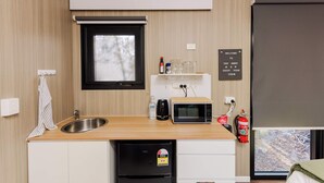 Une petite cuisine équipée d’un évier, d’un four à micro-ondes et d’un petit réfrigérateur.