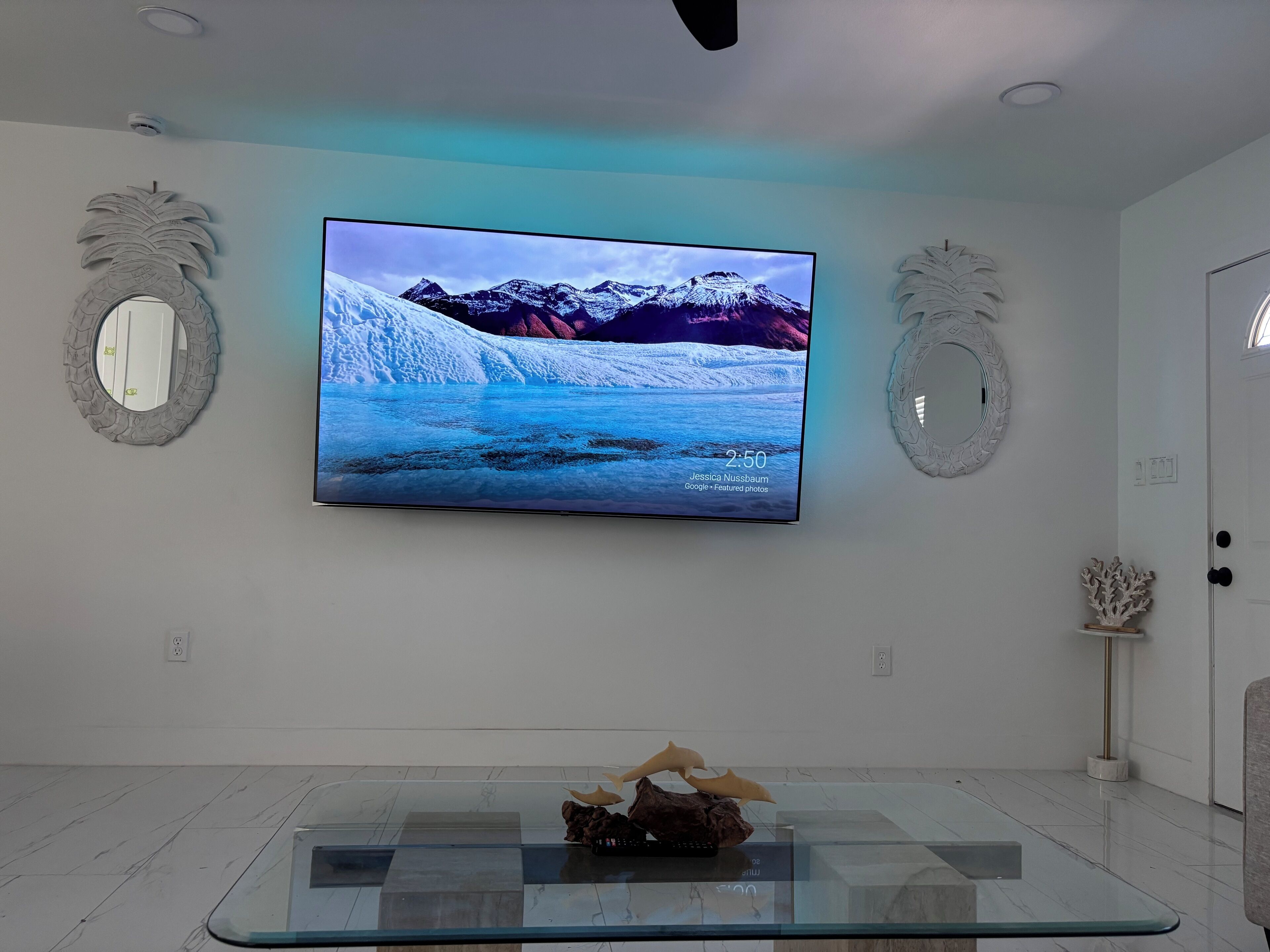 Una sala de estar moderna con un televisor de pantalla plana grande montado en la pared que muestra un paisaje montañoso.