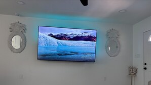 Ett modernt vardagsrum med en stor, platt-TV som är monterad på väggen och visar ett vackert bergslandskap.