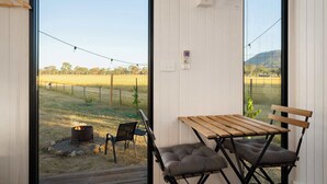 A room with a large window overlooking a fenced outdoor area with a fire pit and chairs.