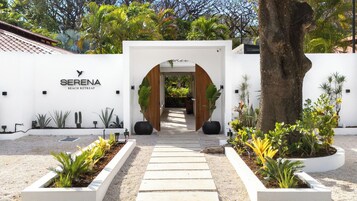 Un edificio blanco con un letrero que dice 'SERENA BEACH RETREAT' y un sendero que conduce a un arco.