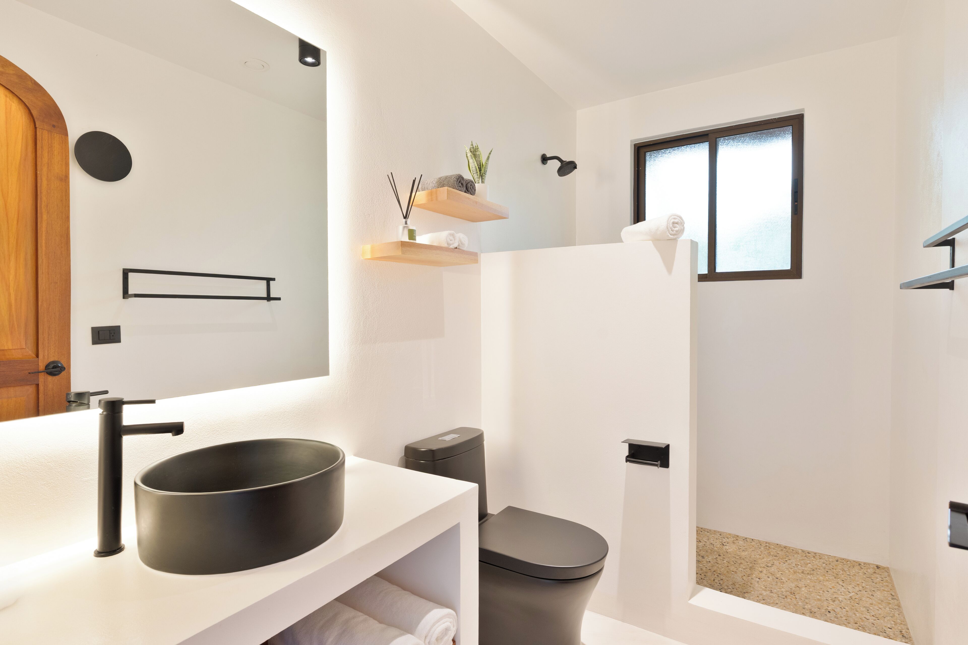 Ein modernes Badezimmer mit einem runden Waschbecken, Toilette und Dusche.