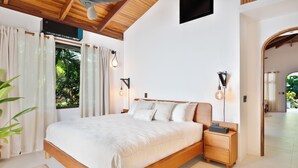 Une chambre avec un lit en bois, des lampes de chevet et une vue sur la verdure.