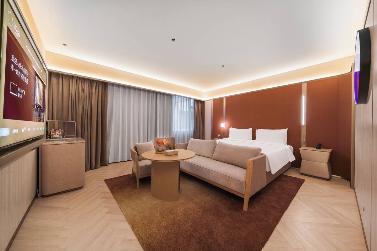 Een hotelkamer met een bed, een slaapbank, nachtkastje en een televisie.