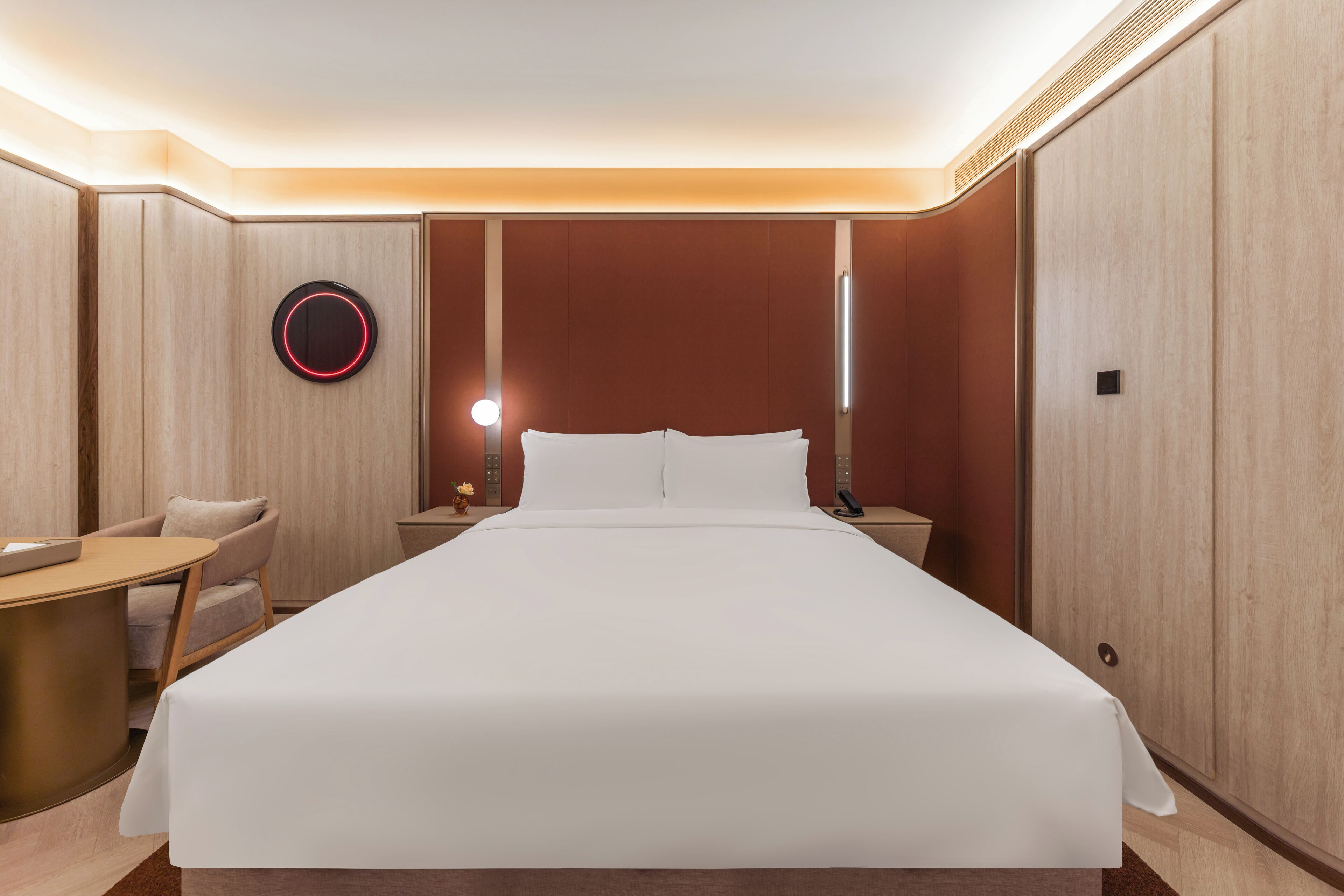 Une chambre d’hôtel avec un grand lit, un bureau, une chaise et une table de chevet avec une lampe.