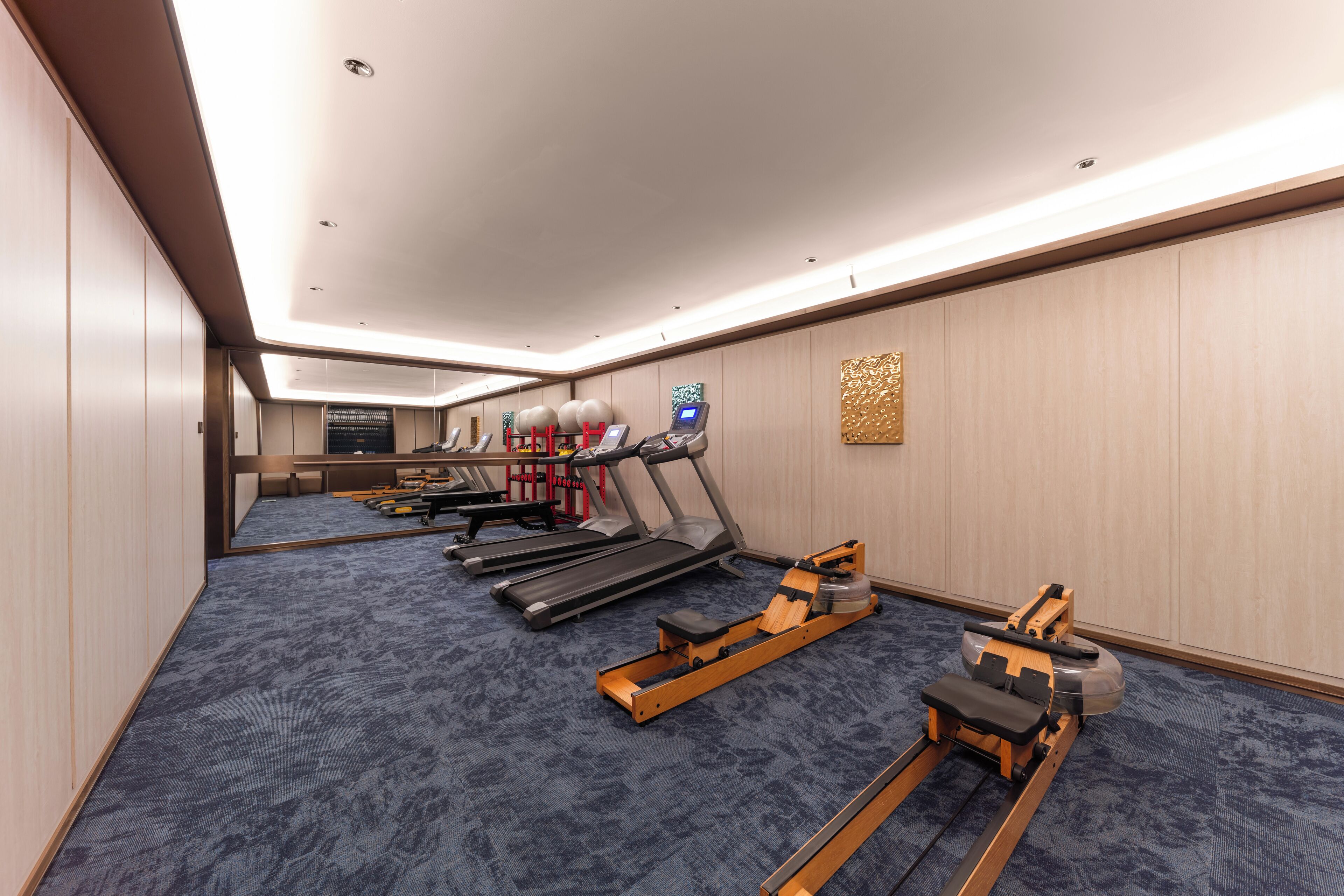 A hotel fitness room with treadmills, a rowing machine, and exercise balls.