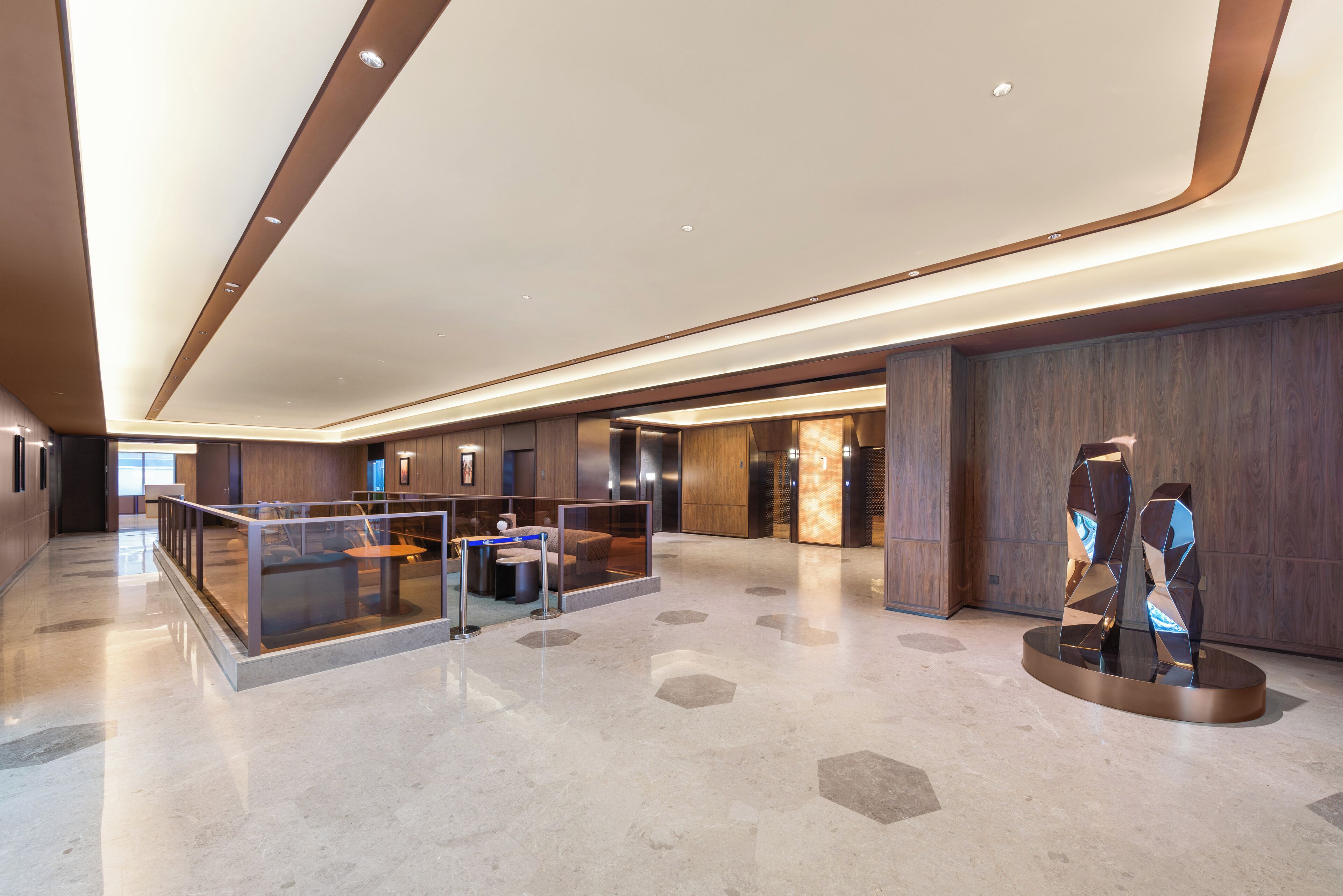Eine großzügige Lobby mit modernem Design, inklusive Glastrennwand, Sitzbereich und einer einzigartigen Kunstinstallation.