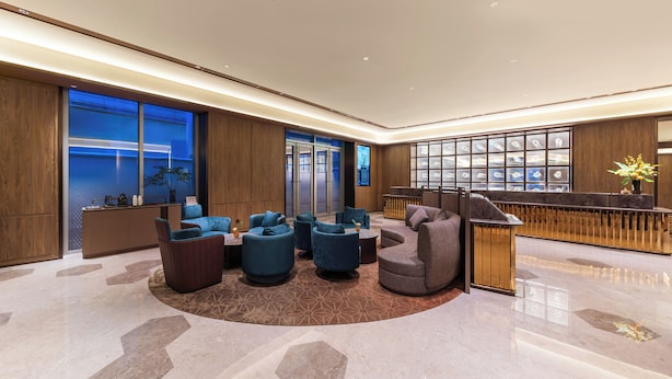 Una lobby moderna con un'area salotto circolare, una reception e ampie finestre con vista sulla città.