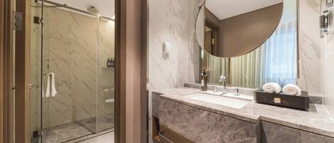 A modern bathroom with a glass shower, a marble sink, and a large mirror.