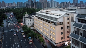 Un edificio moderno con tetto piatto e numerose finestre, immerso in una vivace strada cittadina con auto e autobus.
