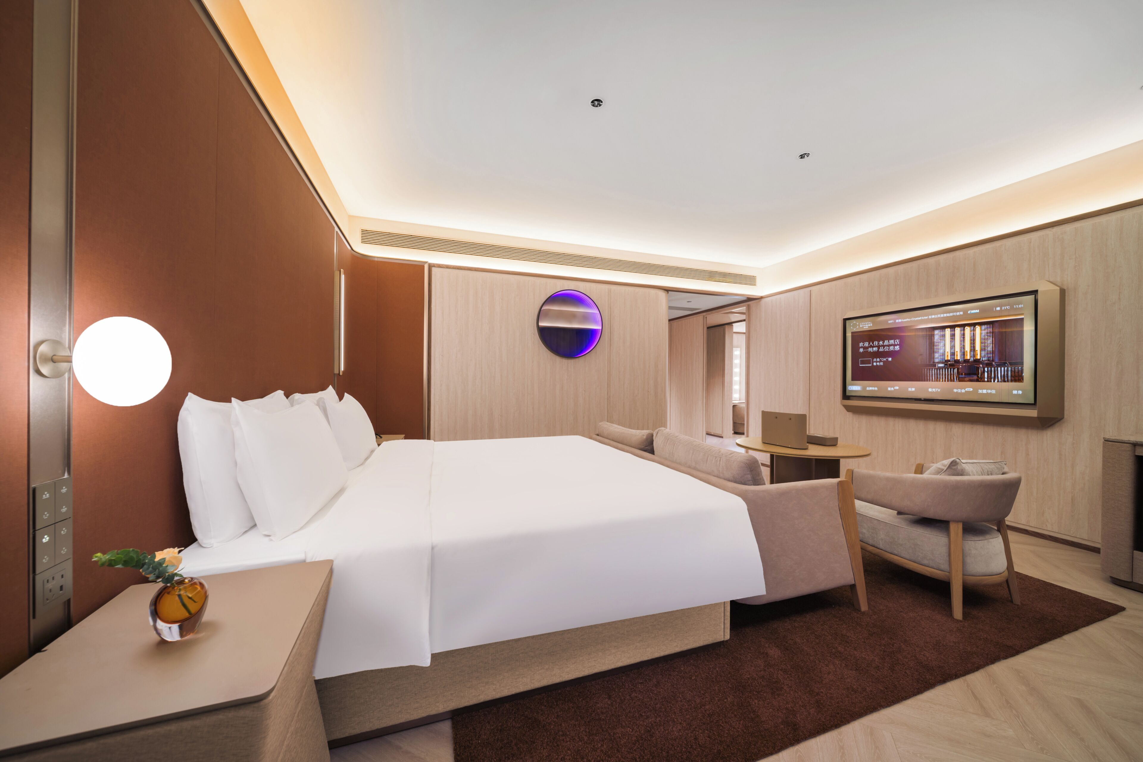 Een moderne hotelkamer met een groot bed, een bureau, een stoel en een televisie aan de muur.