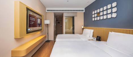 Hotellihuone, jossa on suuri sänky, seinälle asennettu televisio ja koristeellinen seinäpaneeli.