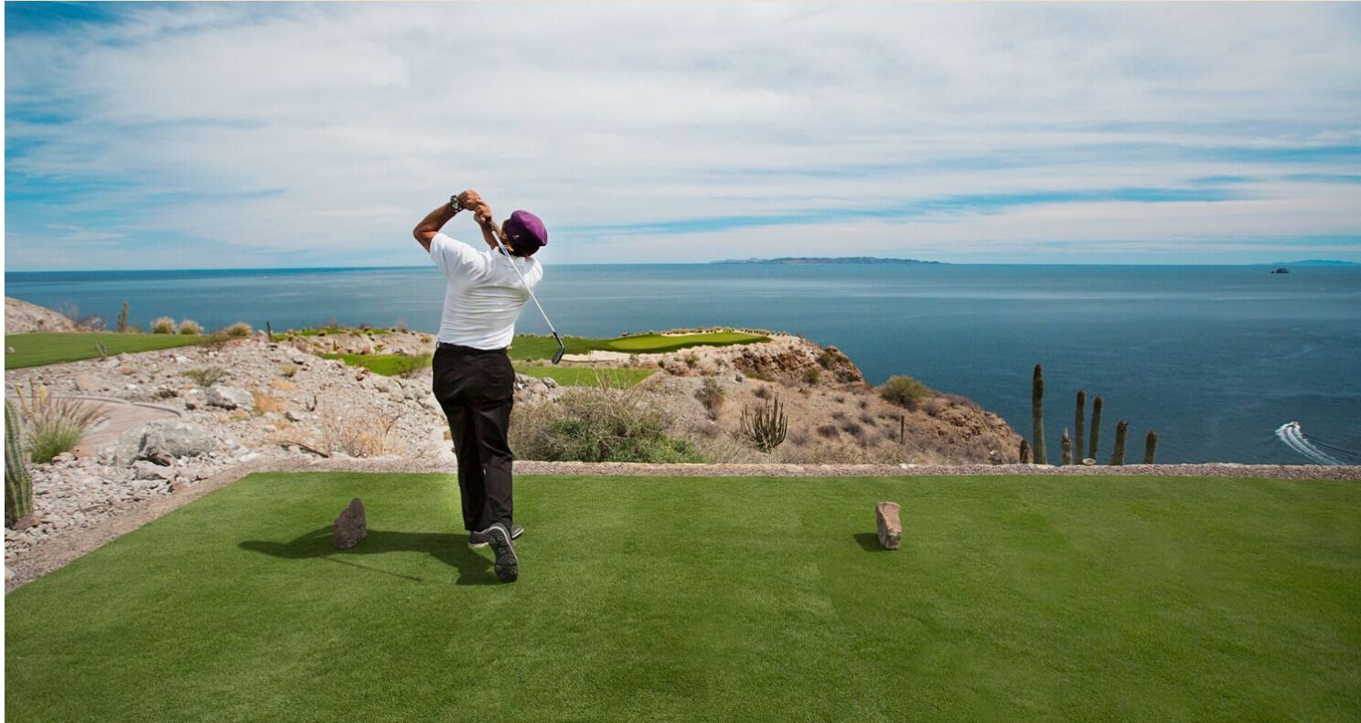 Golfaaja golfkentällä, jolta avautuu näkymä merelle.