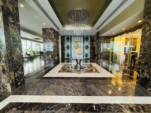 Eine Lobby mit Marmorboden, einem zentralen Dekorationstisch und einer Chandelier.