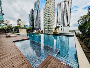 Una piscina en la azotea con cubierta de madera, rodeada de edificios altos.