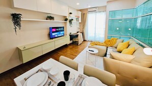 Una sala de estar moderna con televisor, sofá, mesa de comedor y zona de cocina.