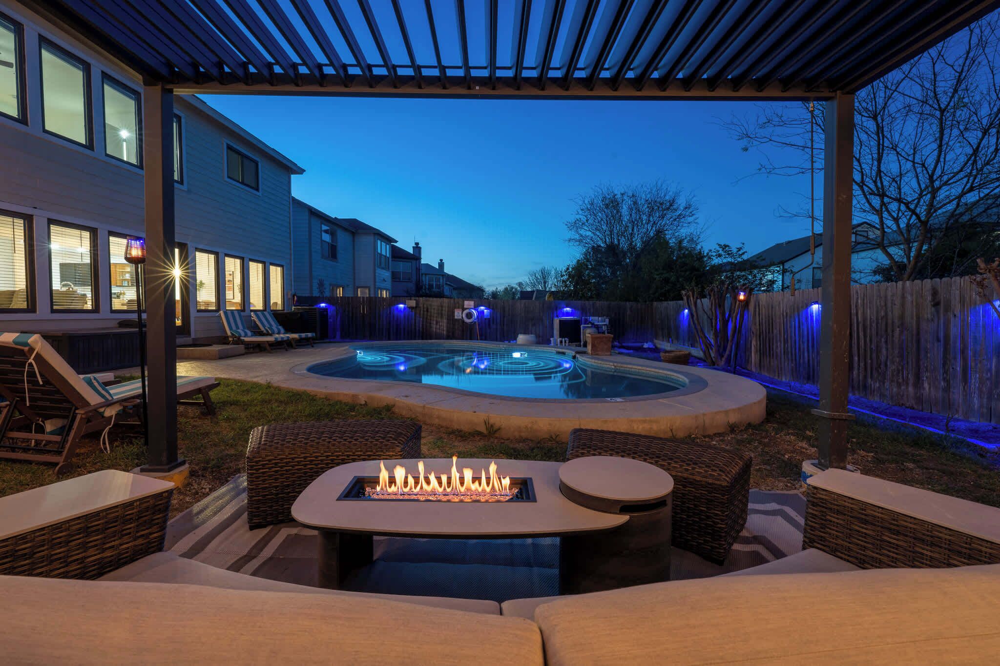 Un jardin avec un jacuzzi, un espace salon extérieur et une pergola.
