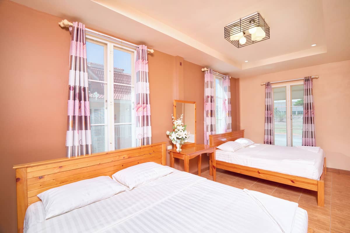 A bedroom with two beds, wooden headboards, a wooden nightstand, a mirror, and a window with curtains.
