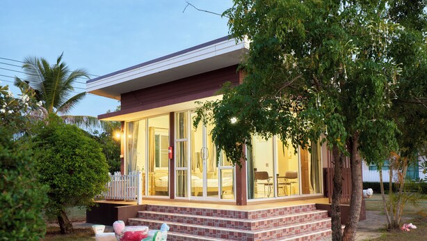 A modern house with a glass front, a porch, and a small garden with two decorative chairs. - The Peak Resort Chaiyaphum (Chaiyaphum)