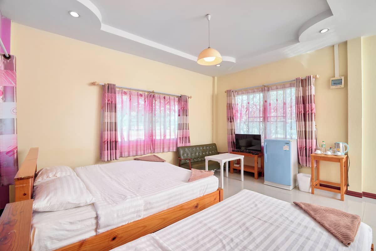 A hotel room with two beds, a television, a refrigerator, and a small table.