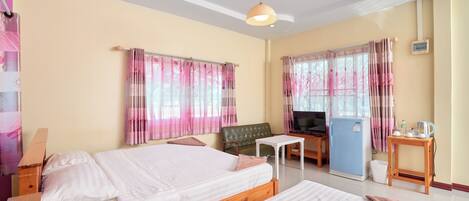 A hotel room with two beds, a television, a refrigerator, and a small table.