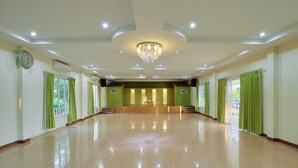 A spacious, well-lit hall with a chandelier, green curtains, and a clock on the wall. - The Peak Resort Chaiyaphum (Chaiyaphum)