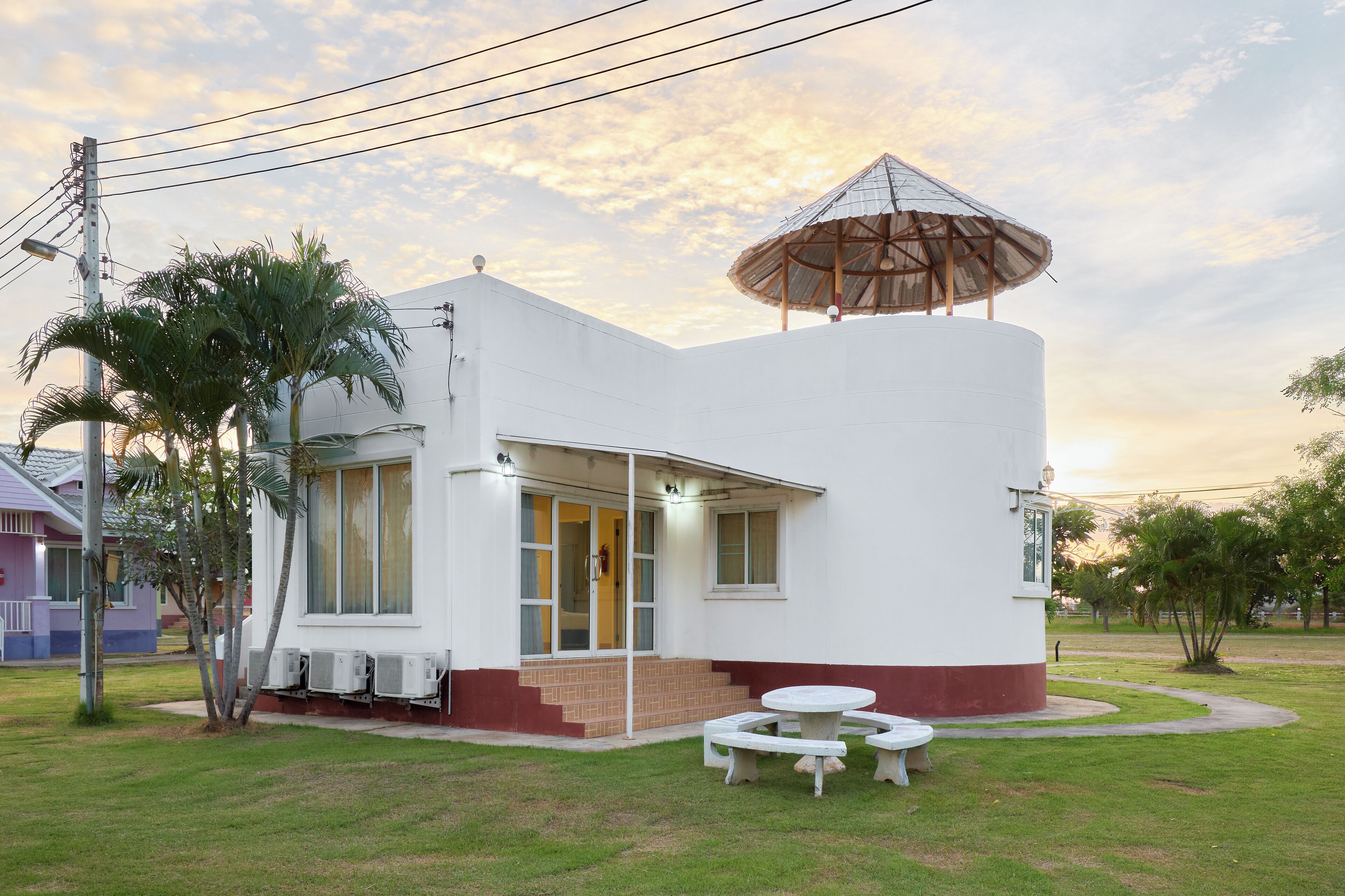 A white building with a covered outdoor seating area and a small garden.