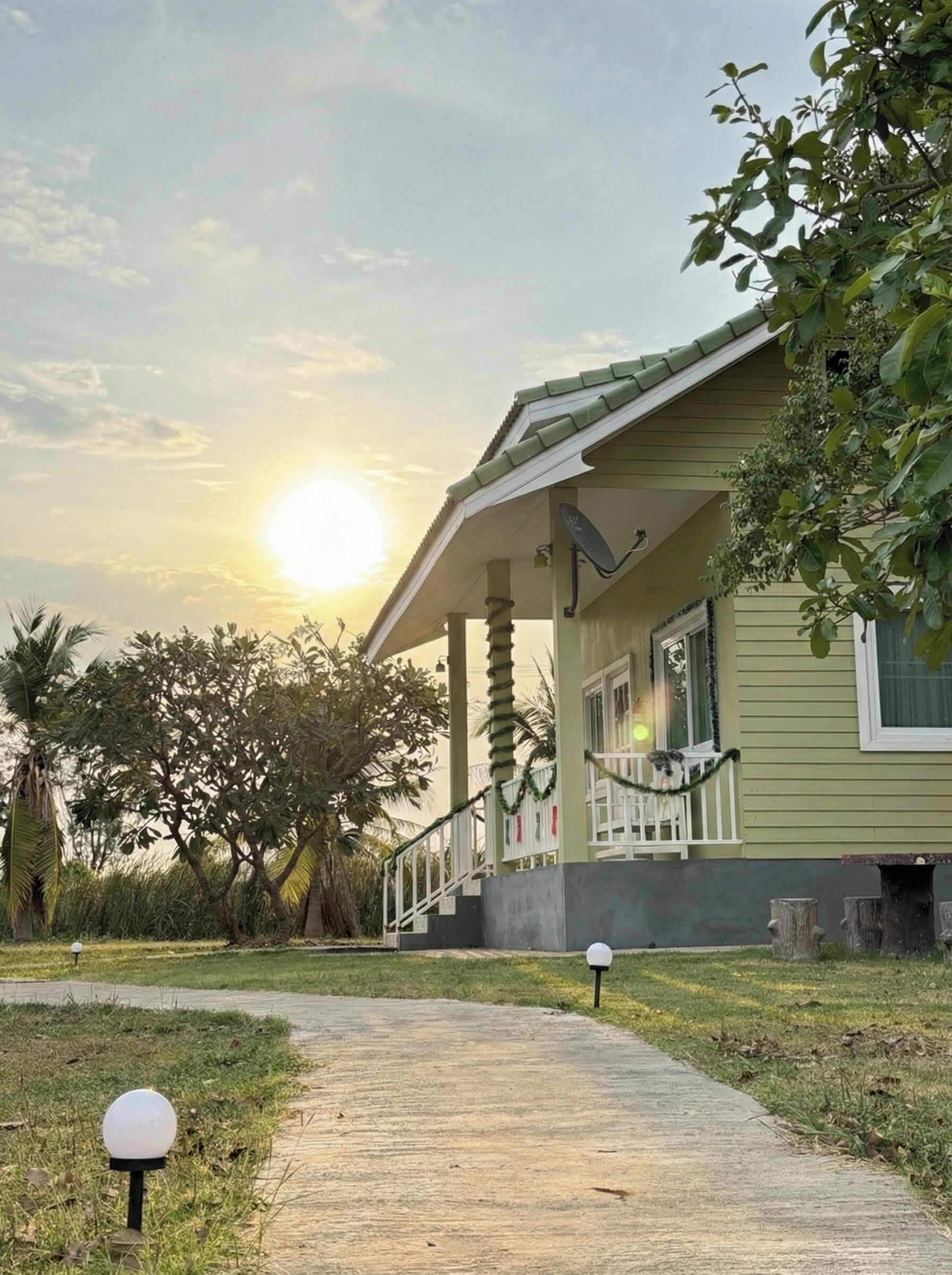 A house with a porch, a pathway leading to it, and a sunset in the background. - The Peak Resort Chaiyaphum (Chaiyaphum)