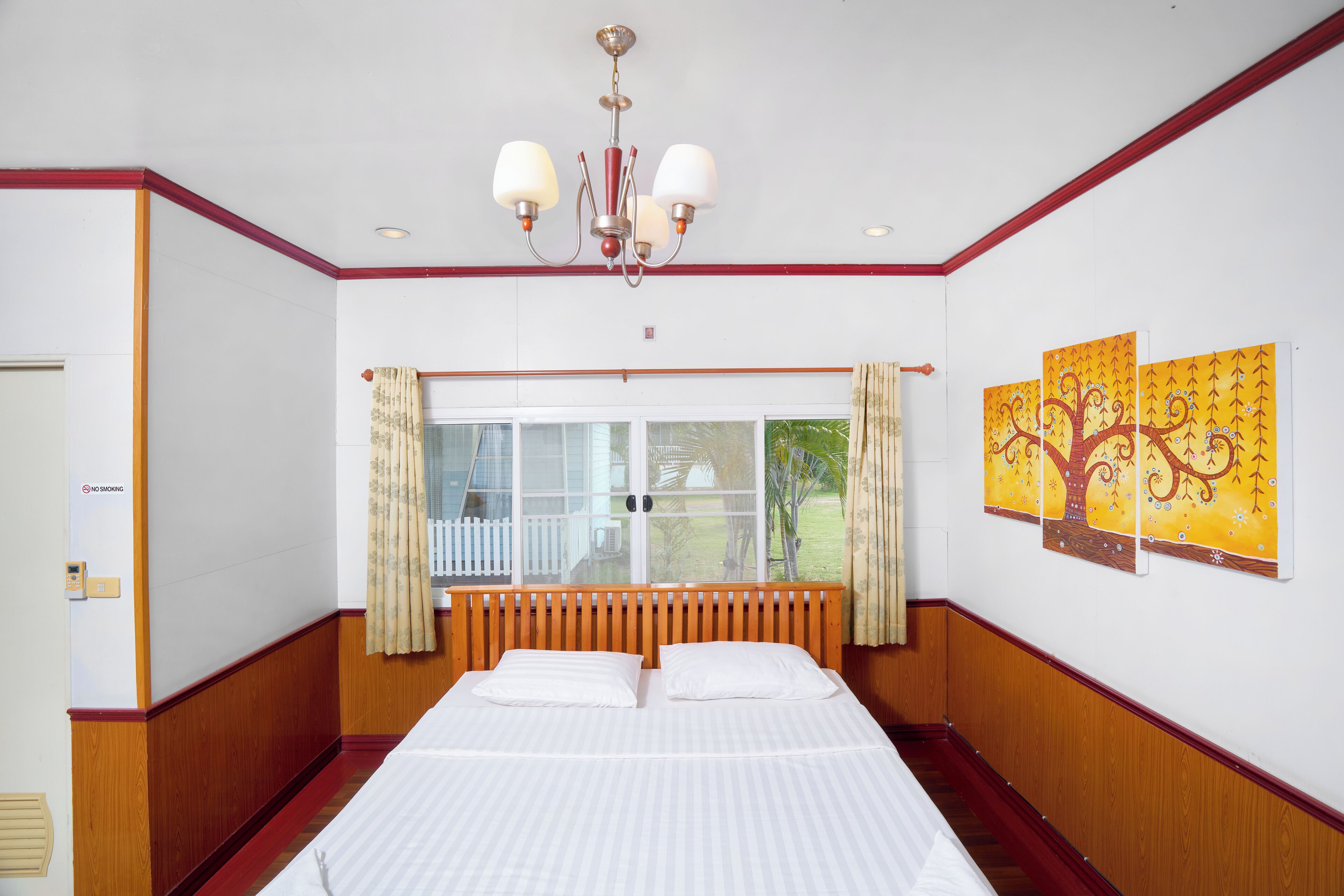 Una habitación de hotel con una cama grande, un candelabro, una ventana con cortinas y obras de arte en la pared.