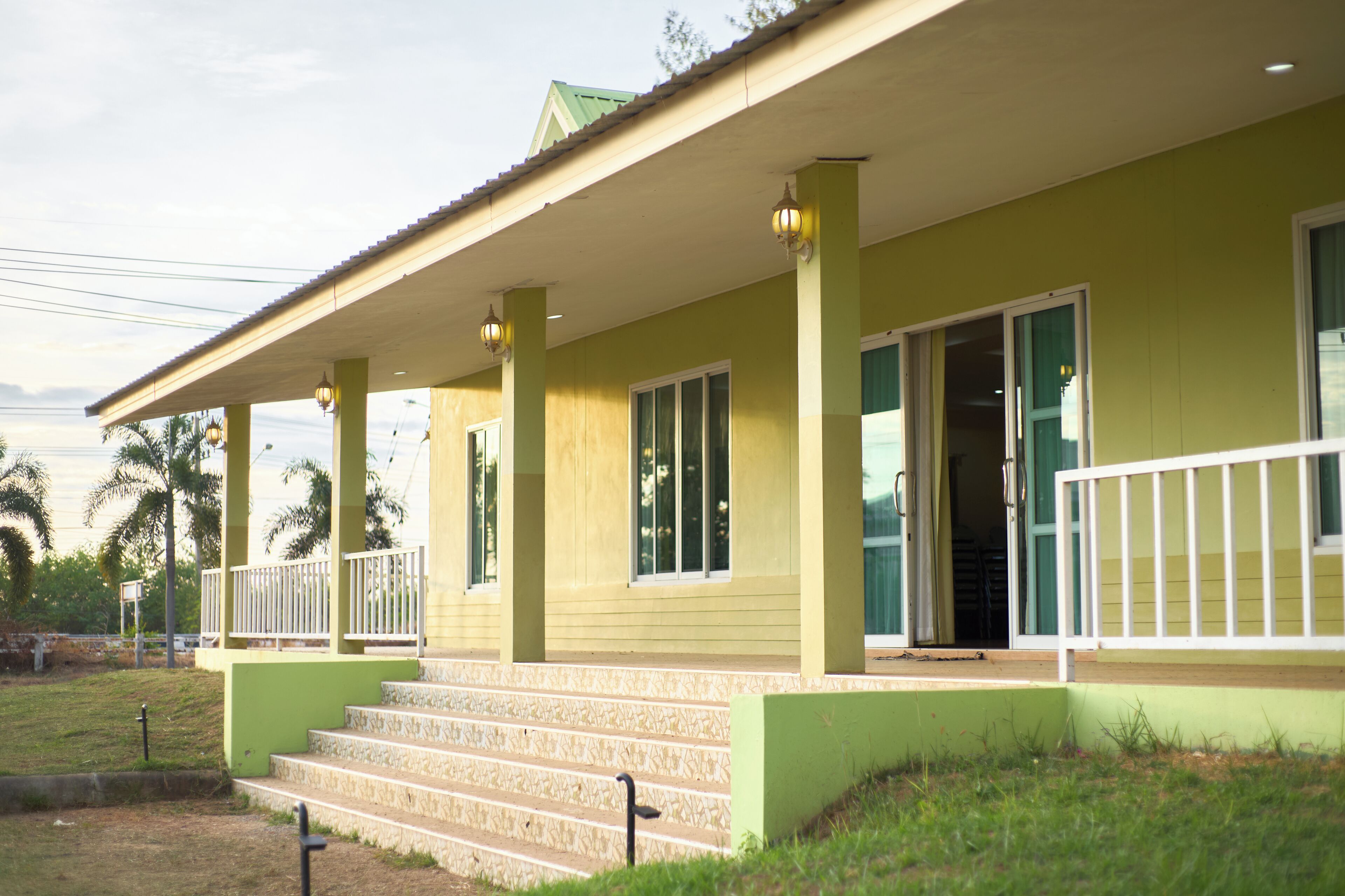 A building with a green exterior, white railings, and a set of stairs leading to a door.