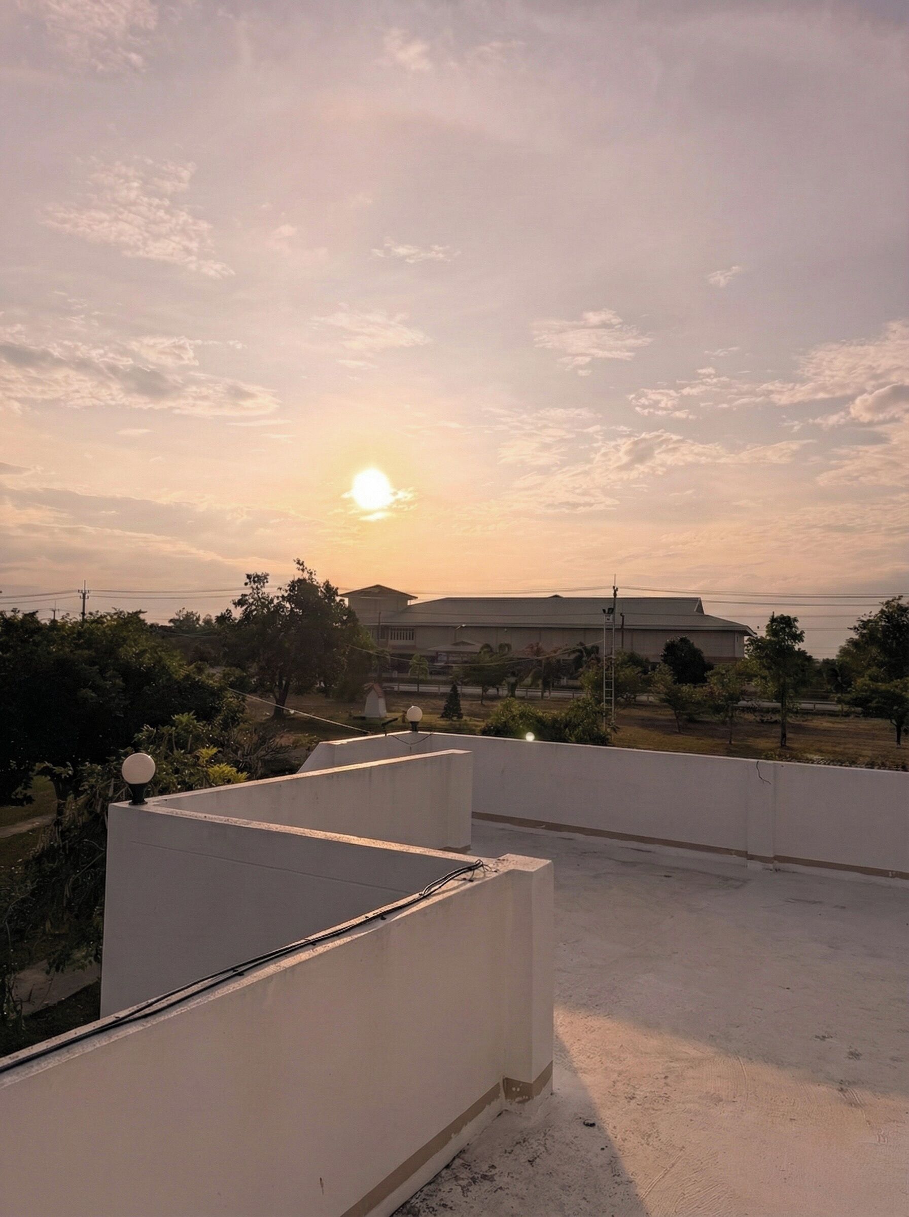 Una terraza en la azotea con vistas a la puesta de sol sobre un edificio lejano.