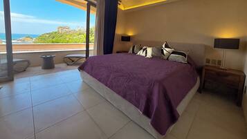 Ein Schlafzimmer mit einem großen Bett, Meerblick und einem Balkon.
